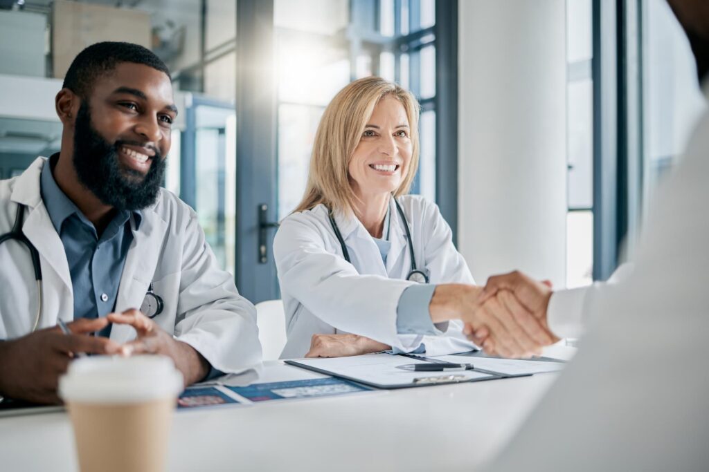 Doctors and a business leader shaking hands to finalize an outsourcing partnership