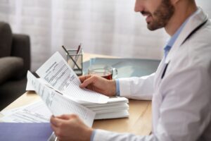 Bearded Professional Reviews Patient Documents in Bright Office